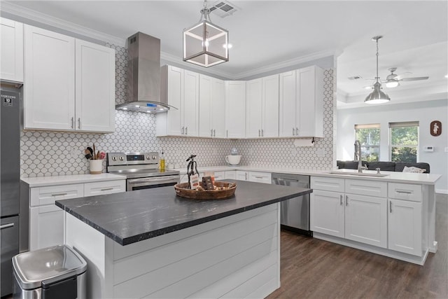 kitchen featuring dark wood-style floors, a peninsula, a sink, stainless steel appliances, and wall chimney range hood