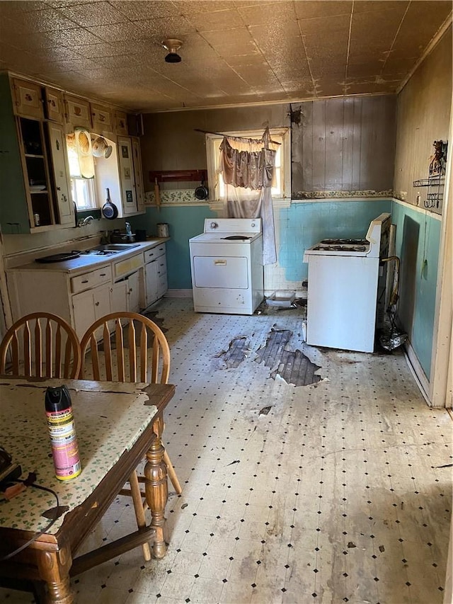 kitchen featuring wooden walls, washer / clothes dryer, light floors, and a sink