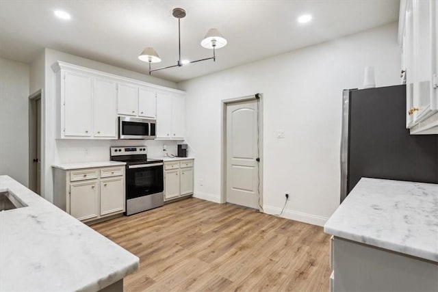 629 S 5th St, Waco, TX 76706 - kitchen with baseboards, light wood-style flooring, stainless steel appliances, hanging light fixtures, and white cabinetry