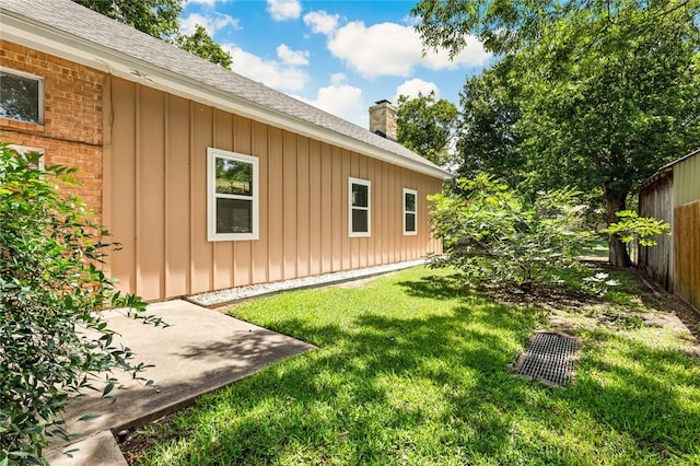 view of property exterior with fence, a chimney, a shingled roof, board and batten siding, and a yard