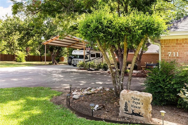 exterior space featuring fence, a lawn, a carport, and concrete driveway