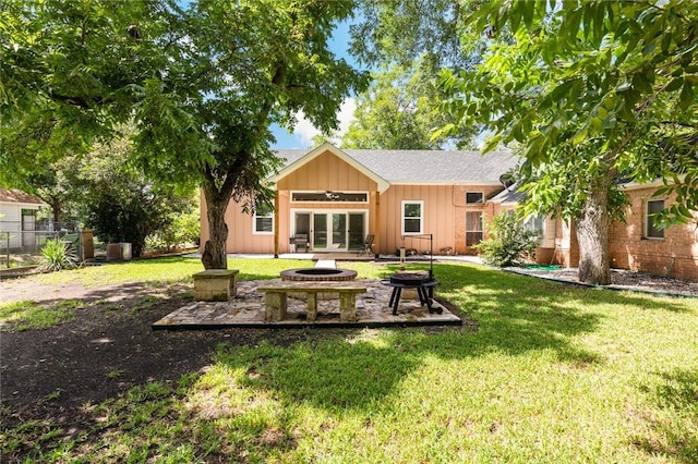 back of property with french doors, board and batten siding, a lawn, and an outdoor fire pit