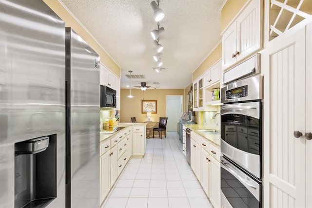 kitchen featuring black appliances, light tile patterned floors, a textured ceiling, a ceiling fan, and a sink