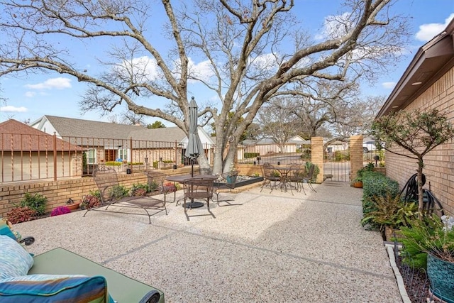 view of patio / terrace featuring a gate, a residential view, outdoor dining space, and fence