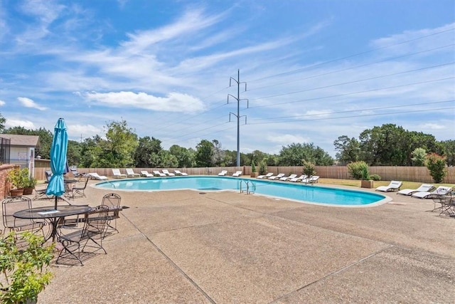 community pool with a fenced backyard and a patio area