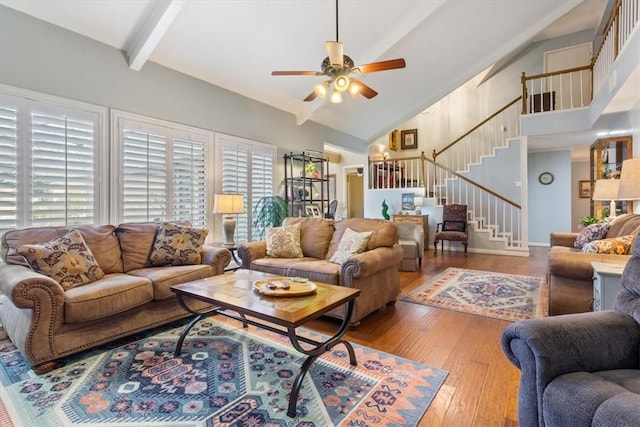 living room with stairway, beam ceiling, hardwood / wood-style flooring, high vaulted ceiling, and a ceiling fan