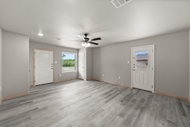 unfurnished living room with baseboards, ceiling fan, light wood finished floors, and visible vents