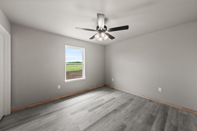 unfurnished room with baseboards, ceiling fan, and wood finished floors