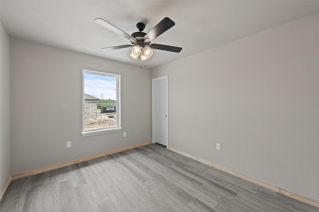spare room featuring a ceiling fan, baseboards, and wood finished floors