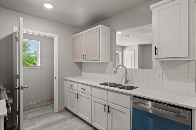 kitchen with visible vents, tasteful backsplash, stainless steel dishwasher, a sink, and light countertops