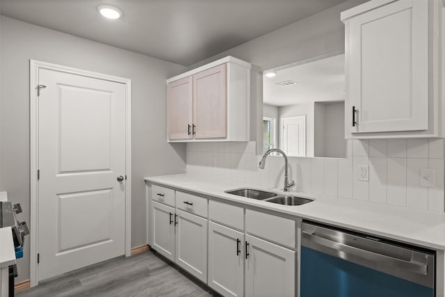 kitchen with a sink, light wood-style floors, light countertops, dishwasher, and visible vents