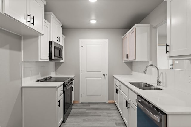kitchen featuring a sink, light wood-style floors, stainless steel appliances, white cabinetry, and decorative backsplash