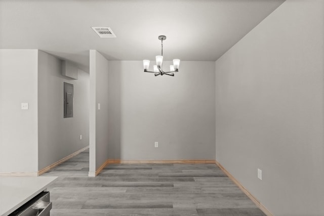 unfurnished dining area with visible vents, baseboards, light wood-type flooring, electric panel, and a chandelier