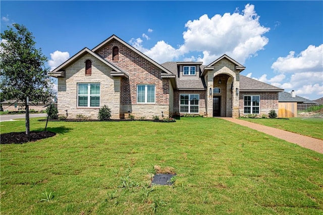 view of front of property with stone siding, a front yard, and roof with shingles