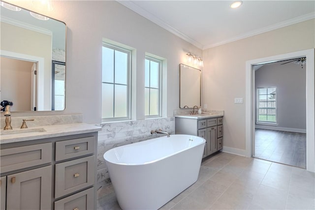 bathroom featuring two vanities, a sink, crown molding, and a freestanding tub