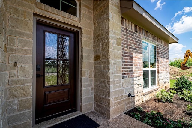 view of exterior entry with stone siding and brick siding