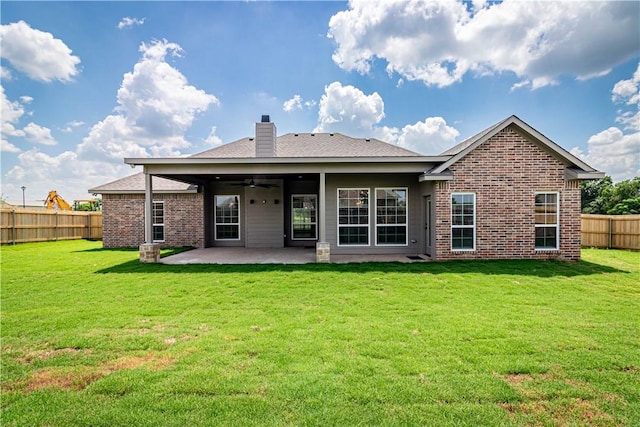 rear view of house with brick siding, ceiling fan, a yard, a fenced backyard, and a patio area