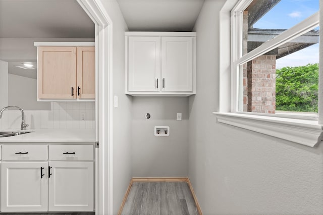 laundry room featuring cabinet space, a sink, hookup for a washing machine, baseboards, and wood finished floors