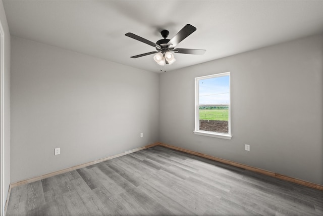 spare room featuring baseboards, ceiling fan, and wood finished floors