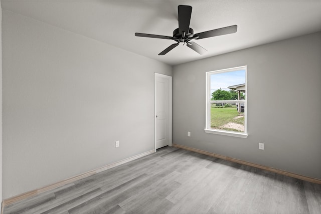 unfurnished room with baseboards, a ceiling fan, and light wood-type flooring