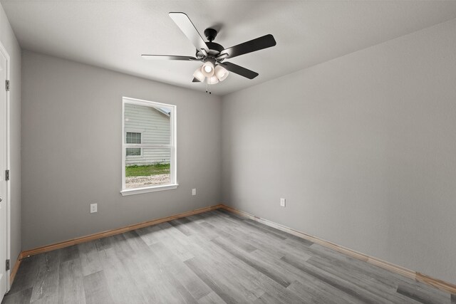 empty room featuring a ceiling fan, baseboards, and wood finished floors