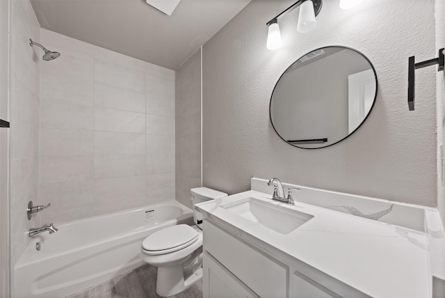 full bath with shower / tub combination, wood finished floors, vanity, toilet, and a textured wall