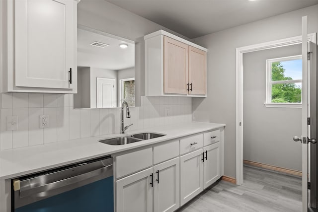 kitchen featuring light wood-type flooring, light countertops, tasteful backsplash, a sink, and dishwasher