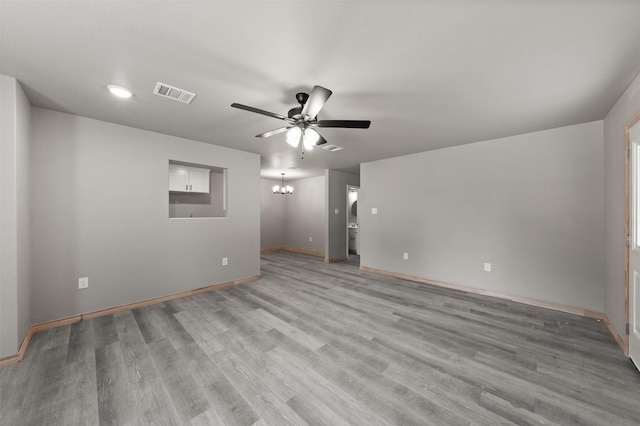 spare room with light wood-style flooring, ceiling fan with notable chandelier, recessed lighting, baseboards, and visible vents
