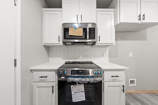 kitchen with appliances with stainless steel finishes, tasteful backsplash, light countertops, baseboards, and white cabinetry