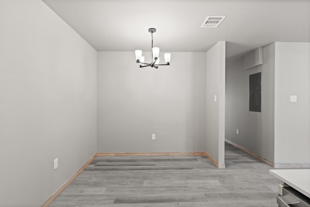 unfurnished dining area featuring light wood-style floors, electric panel, visible vents, baseboards, and an inviting chandelier