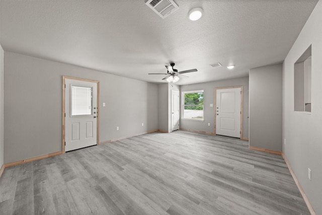unfurnished living room with baseboards, visible vents, and light wood-type flooring