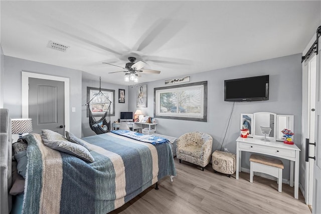 2386 Flat Rock Rd, Waco, TX 76708 - bedroom featuring visible vents, a barn door, light wood-style flooring, and a ceiling fan