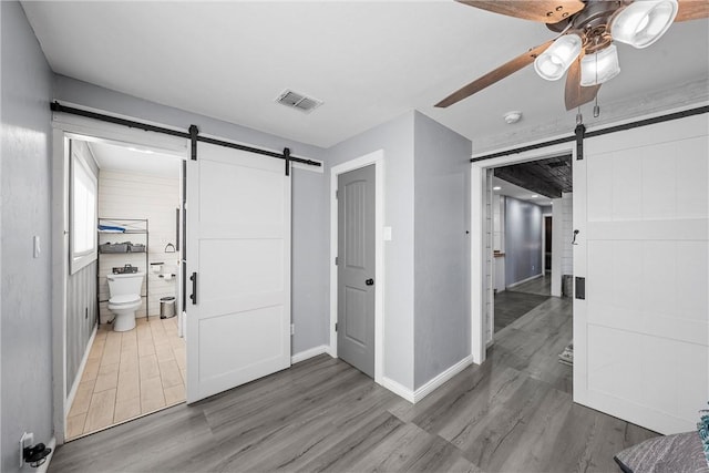 2386 Flat Rock Rd, Waco, TX 76708 - interior space with wood finished floors, visible vents, ceiling fan, ensuite bathroom, and a barn door