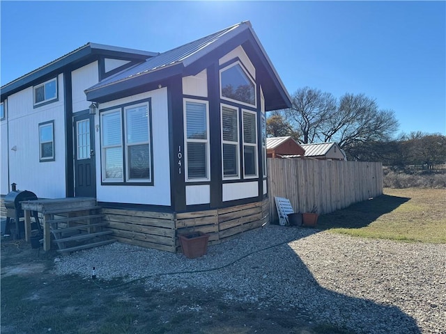 view of side of property featuring fence, entry steps, and metal roof