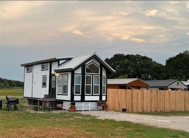 view of front of home featuring metal roof, a sunroom, a front lawn, and fence