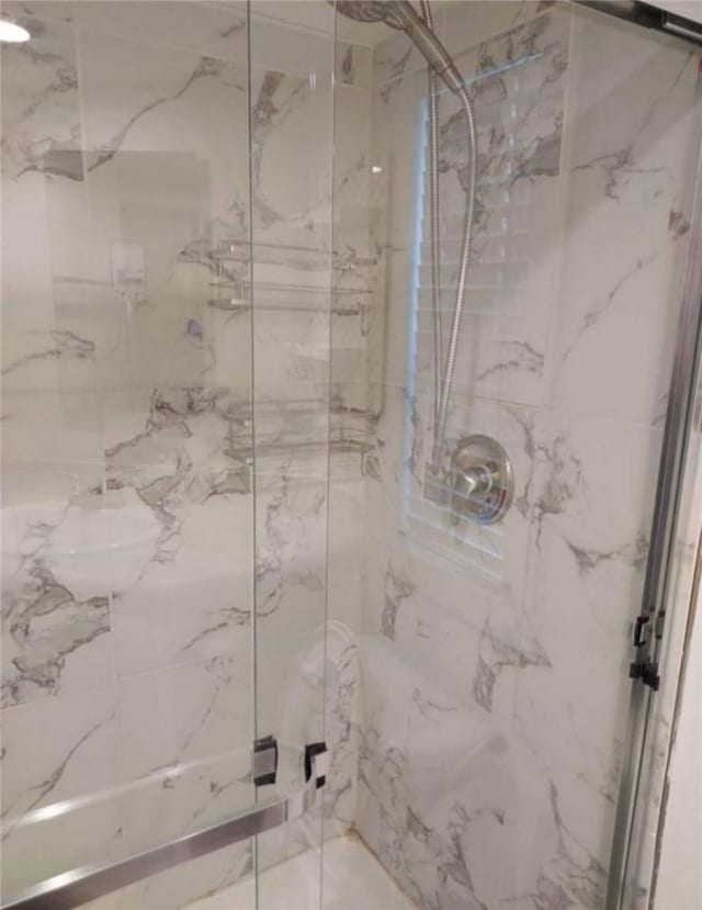 bathroom featuring a marble finish shower