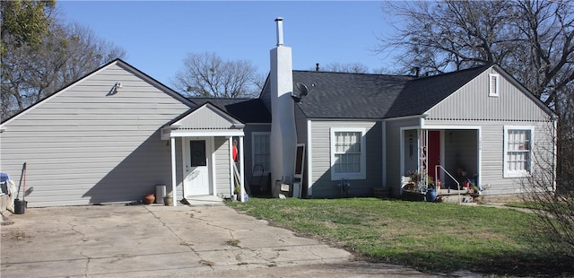 view of front of house featuring a chimney, roof with shingles, and a front yard