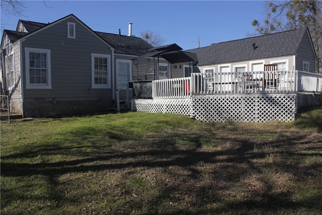rear view of house featuring a wooden deck and a lawn