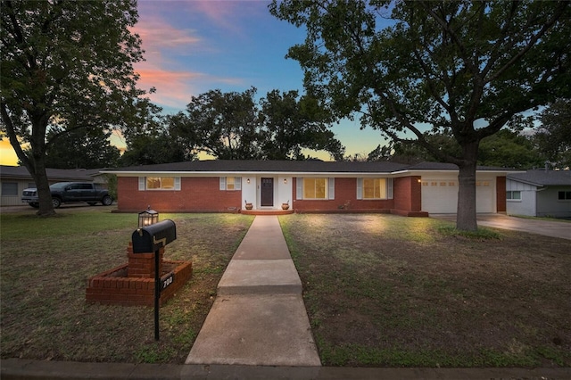 ranch-style home with brick siding, driveway, an attached garage, and a front yard