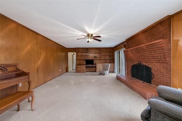 living area featuring light colored carpet, a brick fireplace, wood walls, and ceiling fan