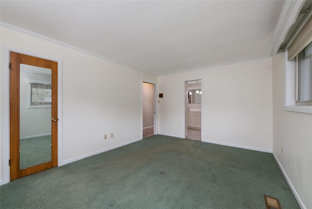 empty room with baseboards, carpet, and crown molding