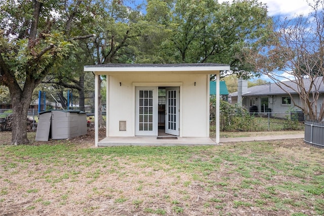 back of property with an outdoor structure, fence, and a lawn