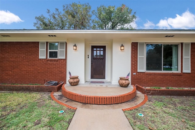 doorway to property with visible vents and brick siding