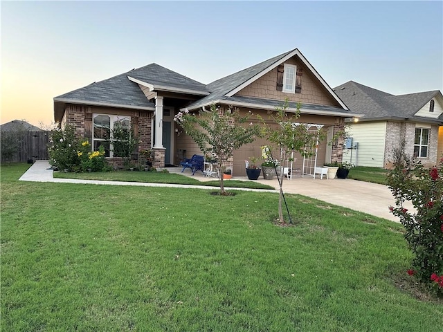 craftsman house featuring brick siding, a lawn, fence, and driveway