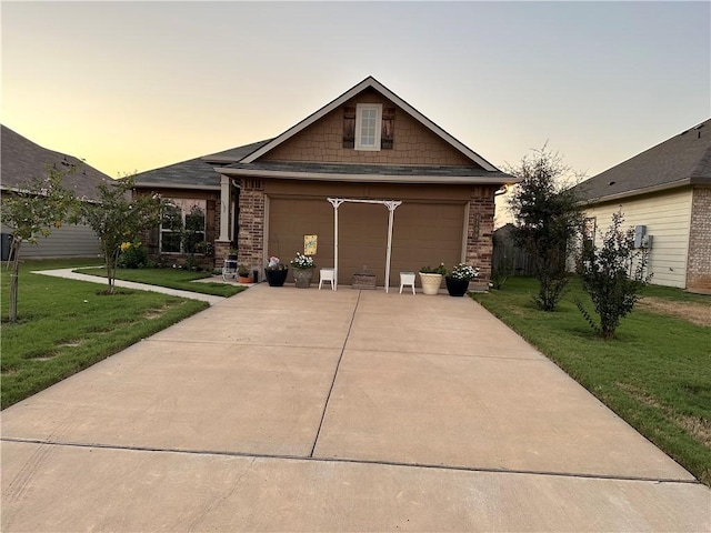 craftsman-style house featuring brick siding, a garage, driveway, and a front yard