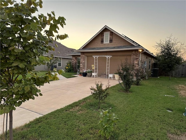 view of front of home with a front yard, concrete driveway, a garage, central air condition unit, and a patio area