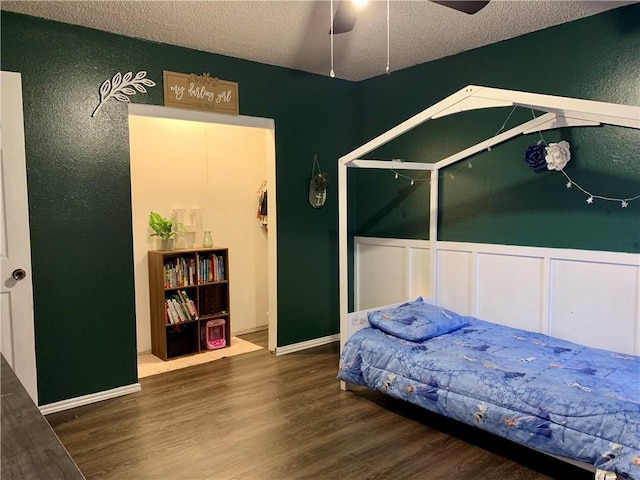 bedroom with a textured ceiling, a ceiling fan, and wood finished floors