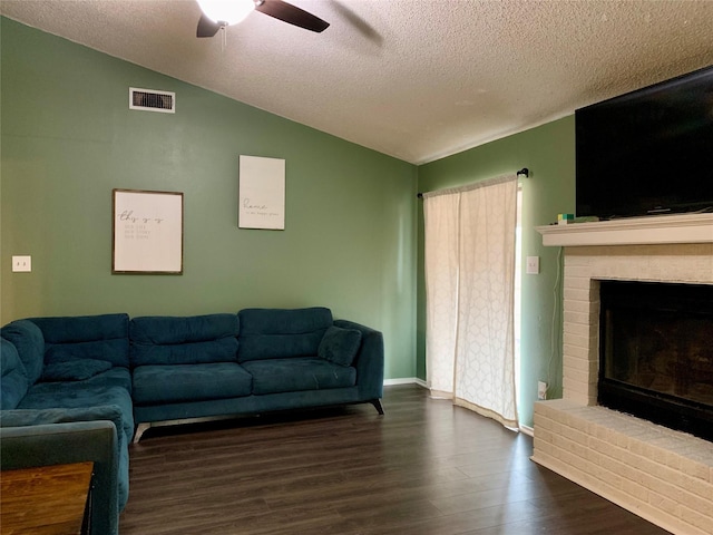 707 Cherry Dr, Groesbeck, TX 76642 - living area with vaulted ceiling, ceiling fan, dark wood finished floors, a textured ceiling, and a fireplace
