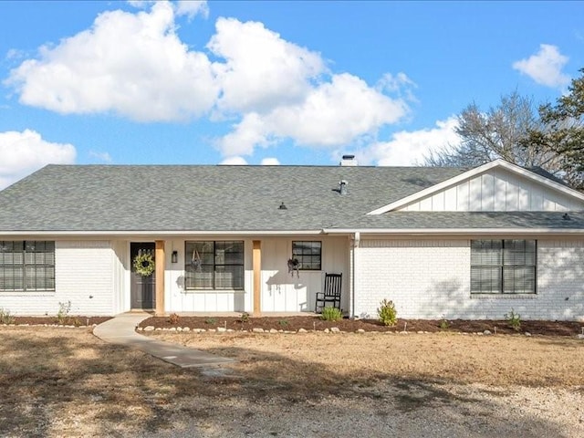 single story home featuring board and batten siding, brick siding, and a shingled roof