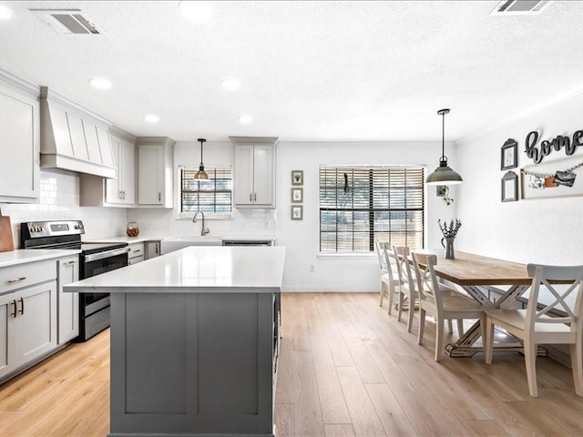 kitchen featuring custom range hood, stainless steel range with electric stovetop, visible vents, and gray cabinets